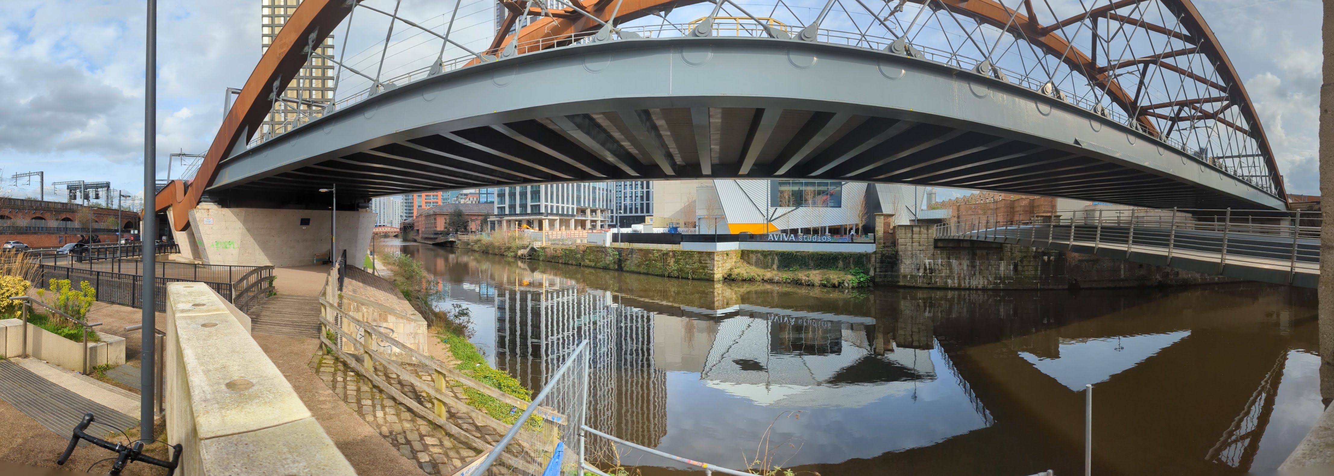 Panoramic view of the River Irwell beneath the sweeping Ordsall Chord railway bridge, with Prince’s Bridge to the right and Aviva Studios visible across the water